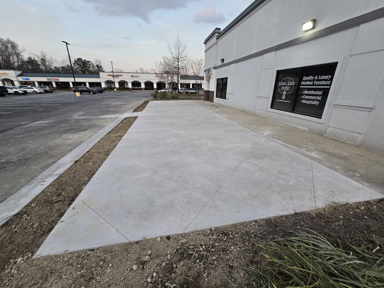 Empty concrete sidewalk and parking lot outside a modern commercial building with white walls