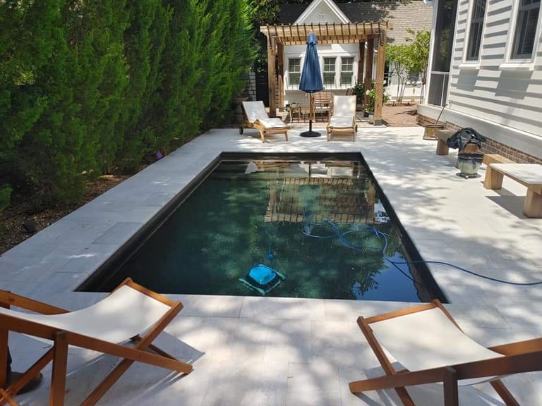 Modern backyard with rectangular swimming pool, wooden lounge chairs, pergola, and house